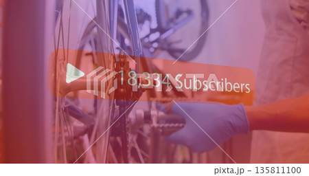 Adjusting mechanic wearing gloves tightening bicycle hub in workshop with sprocket wrench overlay 135811100