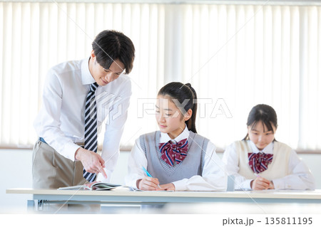 塾で勉強する学生と講師 135811195