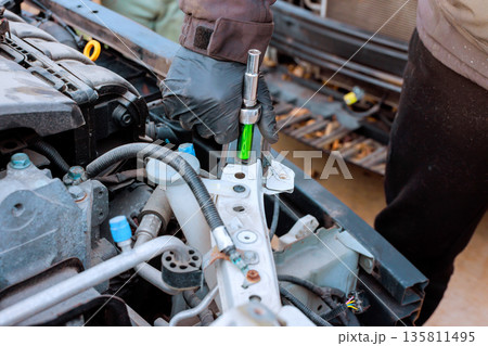 Someone is fixing vehicle using wrench other tools in garage during auto car service 135811495