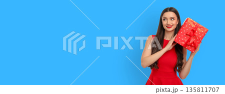Woman in red dress holding a red gift box with a bow Woman in red dress holding a red gift box with a bow 135811707
