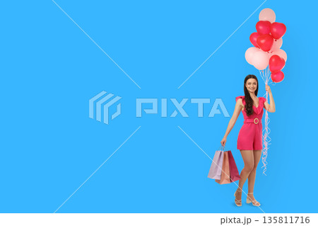 Woman in pink outfit stands with balloons and shopping bags 135811716