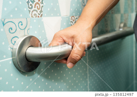Asian woman patient use handrail safety in toilet support rail in bathroom. 135812497