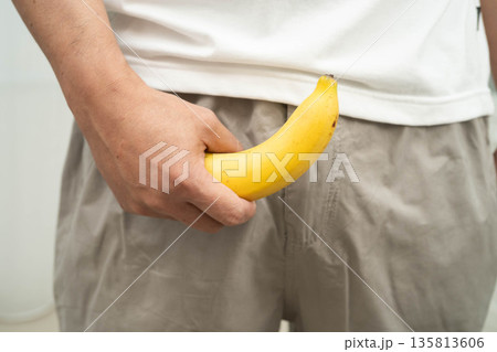 Male stands holding a banana, penis health. Male stands holding a banana, penis health. 135813606