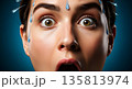 Shocked woman with water splashing on her face against blue background 135813974