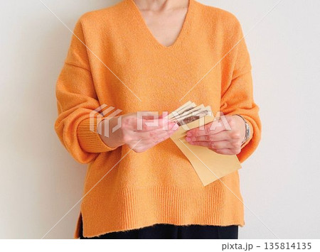 茶封筒に入ったお金を数える主婦 茶封筒に入ったお金を数える主婦 135814135