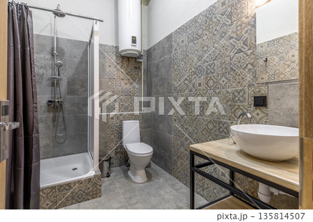 Modern hostel bathroom with walk-in shower, toilet, and vessel sink 135814507