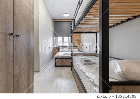 Modern hostel dormitory with industrial bunk beds and wooden wardrobe 135814509