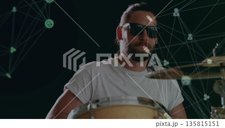 Bearded drummer playing drum kit with sunglasses in studio with glowing green node line graphics Bearded drummer playing drum kit with sunglasses in studio with glowing green node line graphics 135815151