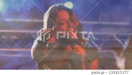 Singing singer holding handheld mic reaching toward audience on music stage with truss lights, haze 135815177