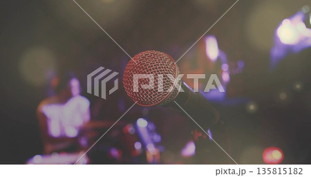 Focusing mic on stand capturing bandmates playing guitar and keyboard at club with lights and haze Focusing mic on stand capturing bandmates playing guitar and keyboard at club with lights and haze 135815182