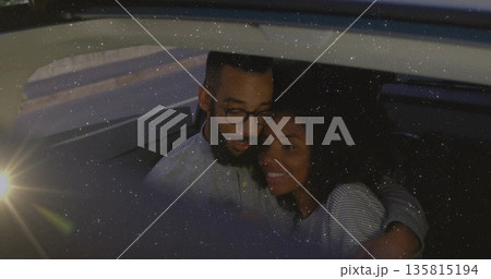 Leaning couple buckling seat belt, embracing in backseat at night, amid side window headlight glare Leaning couple buckling seat belt, embracing in backseat at night, amid side window headlight glare 135815194