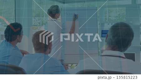 Presenting female doctor writing medical on flipchart in hospital conference room, with blue marker 135815223