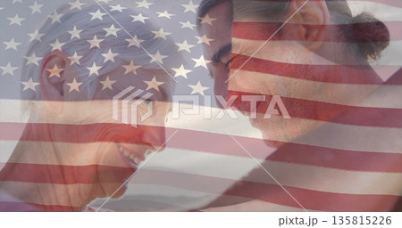 Sharing mature couple touching foreheads and smiling at shoreline, with American flag overlay Sharing mature couple touching foreheads and smiling at shoreline, with American flag overlay 135815226