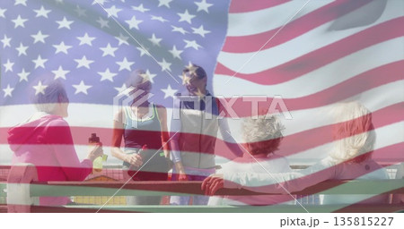 Gathering women on waterfront bench holding water bottle and fitness bag, American flag overlay 135815227