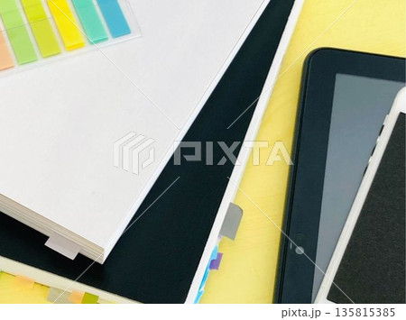 机の上の本とノートとタブレットとスマホ 135815385