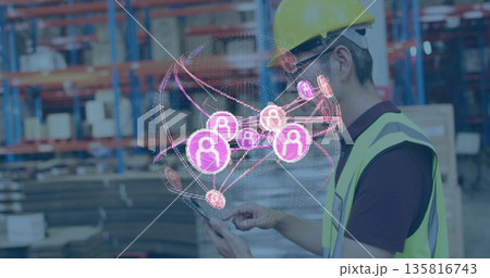 Interacting worker wearing safety helmet using tablet in warehouse with network display, copy space 135816743