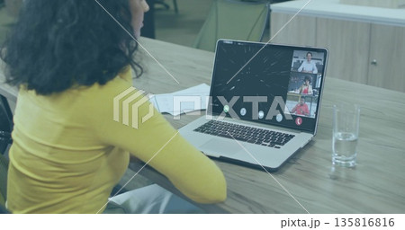 Sitting Hispanic woman typing on laptop at conference table, with papers and clear glass of water Sitting Hispanic woman typing on laptop at conference table, with papers and clear glass of water 135816816