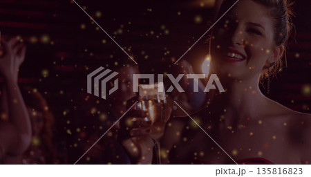 Smiling attendee in red dress holding champagne glass at lounge amid golden sparkles, copy space Smiling attendee in red dress holding champagne glass at lounge amid golden sparkles, copy space 135816823