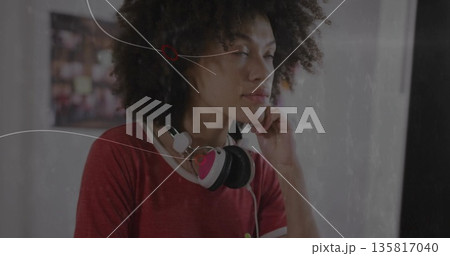 Woman resting head on hand in studio, wearing red shirt and pink-and-white over-ear headphones Woman resting head on hand in studio, wearing red shirt and pink-and-white over-ear headphones 135817040