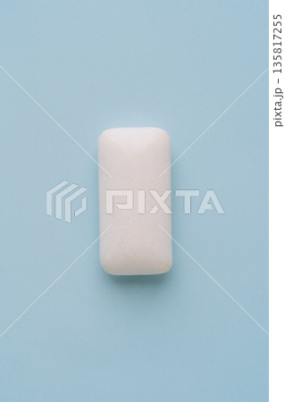 Single white chewing gum piece on light blue background, minimal concept 135817255