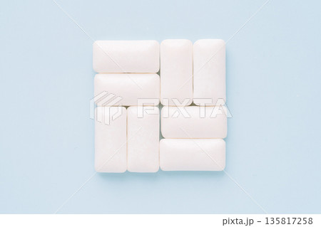 White chewing gum pieces arranged in a grid on light blue background 135817258