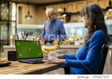 Isolated mockup with elderly woman enjoying breakfast at kitchen table, serving fresh coffee and pastry. Senior married people feeling happy with their retirement lifestyle at home. Isolated mockup with elderly woman enjoying breakfast at kitchen table, serving fresh coffee and pastry. Senior married people feeling happy with their retirement lifestyle at home. 135817327