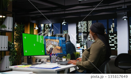 Isolated mockup and CAD software used by black female graphic designer to create a modern layout, 3D modeling program and chroma key on dual monitors. Architectural design assets. Camera A. 135817649