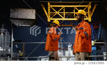 African american environmental officer communicates via radio device on offshore platform, emission tracking to manage petroleum and natural gas extraction from marine habitat. African american environmental officer communicates via radio device on offshore platform, emission tracking to manage petroleum and natural gas extraction from marine habitat. 135817685