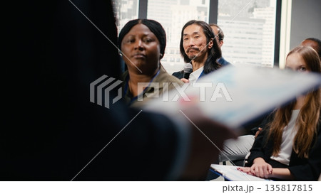 Asian businessman in audience interacting with presenter, asking questions and engaging in debate. Mixed age participants include managers, employees, shareholders and investors at summit. Asian businessman in audience interacting with presenter, asking questions and engaging in debate. Mixed age participants include managers, employees, shareholders and investors at summit. 135817815