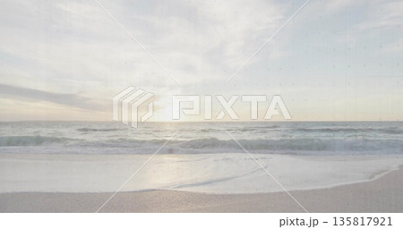 Rolling ocean waves approaching smooth sandy shoreline at sunset, under scattered pastel clouds Rolling ocean waves approaching smooth sandy shoreline at sunset, under scattered pastel clouds 135817921