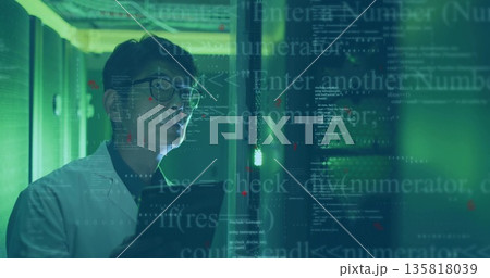 Inspecting technician in lab coat with tablet by racks in server aisle, floating code, copy space 135818039