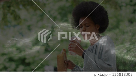 Holding white coffee cup near mouth, woman in grey blouse in park with paper bag Holding white coffee cup near mouth, woman in grey blouse in park with paper bag 135818305