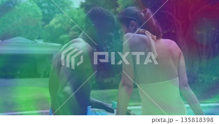 Chatting man in swim trunks and woman in halter swimsuit at suburban backyard pool, with smartphone 135818398