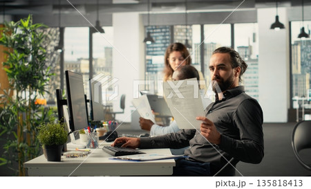 Diverse business staff gathered for briefing in multinational company office. The work agenda covers insights and targets as team reviews documents and diagrams for reports. Diverse business staff gathered for briefing in multinational company office. The work agenda covers insights and targets as team reviews documents and diagrams for reports. 135818413