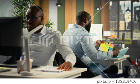 Staff in corporate room discussing business strategy and market research. Diverse coworkers evaluate documents and diagrams to align goals, targets and performance metrics. Staff in corporate room discussing business strategy and market research. Diverse coworkers evaluate documents and diagrams to align goals, targets and performance metrics. 135818416