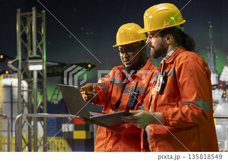 Environmental officers crew on offshore platform deck tracking carbon footprint using tablet. Drilling rig teamworking colleagues ensuring sustainable practices during 24 hour operation Environmental officers crew on offshore platform deck tracking carbon footprint using tablet. Drilling rig teamworking colleagues ensuring sustainable practices during 24 hour operation 135818549