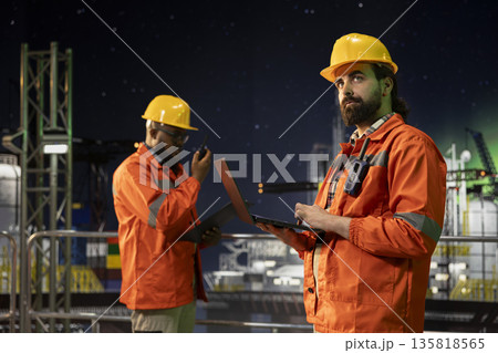 Industrial drilling rig engineering team inspecting equipment integrity using laptop. Offshore sea platform employees performing preventative maintenance checks on machinery to ensure safety Industrial drilling rig engineering team inspecting equipment integrity using laptop. Offshore sea platform employees performing preventative maintenance checks on machinery to ensure safety 135818565