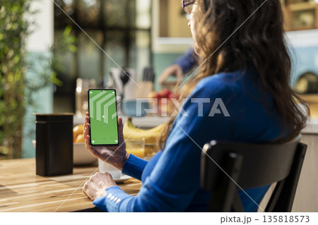 Chroma key display on phone with mature man enjoying retired life at home, relaxing at the kitchen table for breakfast. Space with homemade meal and coffee for good morning routine. Chroma key display on phone with mature man enjoying retired life at home, relaxing at the kitchen table for breakfast. Space with homemade meal and coffee for good morning routine. 135818573