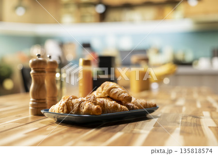 Empty kitchen table with croissants and homemade food for breakfast, contemporary apartment. Bright space with stylish kitchenware, fresh fruits and condiments on the counter, cozy home. Empty kitchen table with croissants and homemade food for breakfast, contemporary apartment. Bright space with stylish kitchenware, fresh fruits and condiments on the counter, cozy home. 135818574