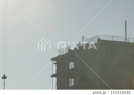 Constructors install steel reinforcement bars to rise new residence building during sunny day. Laborers working on unfinished tall apartment complex, concept of rapid urban growth Constructors install steel reinforcement bars to rise new residence building during sunny day. Laborers working on unfinished tall apartment complex, concept of rapid urban growth 135818588