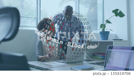 Business colleagues pointing, reviewing documents on laptop at office desk with block chain graphic Business colleagues pointing, reviewing documents on laptop at office desk with block chain graphic 135819706