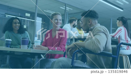 Chatting three coworkers including wheelchair user holding coffee around low table in office lounge Chatting three coworkers including wheelchair user holding coffee around low table in office lounge 135819846