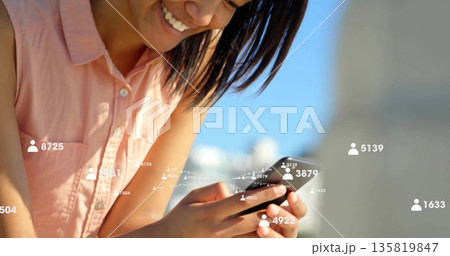 Smiling Hispanic woman tapping smartphone on rooftop, with follower count overlays, copy space Smiling Hispanic woman tapping smartphone on rooftop, with follower count overlays, copy space 135819847
