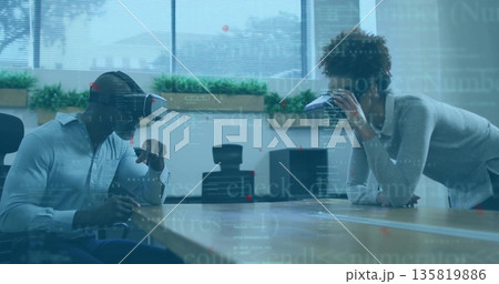 Colleague wearing VR headset exploring code at office conference table, with coffee cup, copy space Colleague wearing VR headset exploring code at office conference table, with coffee cup, copy space 135819886