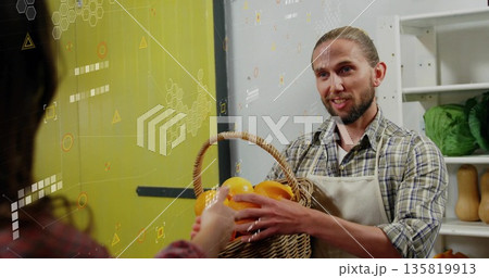 Extending aproned vendor holding wicker orange basket inside produce aisle, with lettuce and squash 135819913