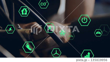 Gripping electrical cables and connectors inside control panel, displaying green hex energy icons 135819956