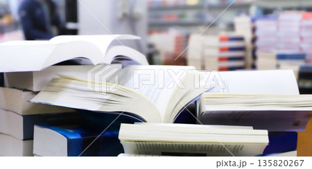 stack of books, close up. Open book on the table in library. Back to school concept. Open book on table with blur bookshelf background 135820267