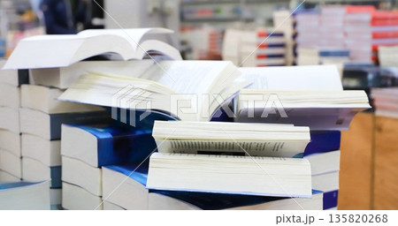 stack of books, close up. Open book on the table in library. Back to school concept. Open book on table with blur bookshelf background stack of books, close up. Open book on the table in library. Back to school concept. Open book on table with blur bookshelf background 135820268