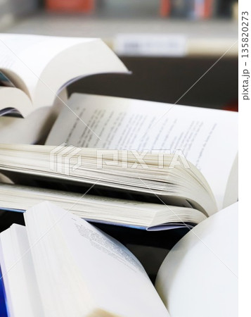 stack of books, close up. Open book on the table in library. Back to school concept. Open book on table with blur bookshelf background 135820273