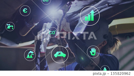 Operating gloved technician grinding chassis with grinder at workshop, with CO? and currency icons Operating gloved technician grinding chassis with grinder at workshop, with CO? and currency icons 135820962